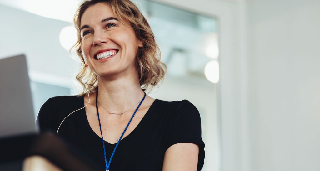 Smiling woman wearing a lanyard and a headset microphone